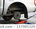 The side view shows the jack and tools used to lift the vehicle and remove the wheel. 137905320