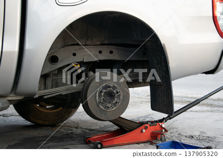 The side view shows the jack and tools used to lift the vehicle and remove the wheel. The side view shows the jack and tools used to lift the vehicle and remove the wheel. 137905320