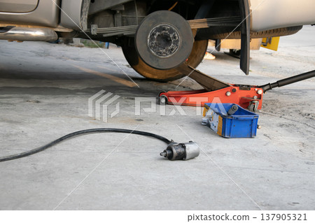 The side view shows the jack and tools used to lift the vehicle and remove the wheel. 137905321