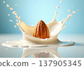 An almond splashes into a pool of milk, creating a dynamic splash effect. The background is a soft blue, enhancing the freshness of the scene. 137905345