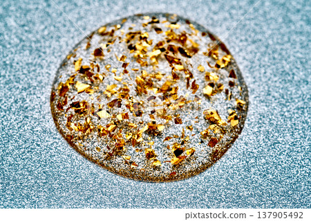 Clear liquid drop filled with glittering gold leaf Clear liquid drop filled with glittering gold leaf 137905492