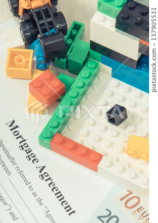 Unfinished house made of toy blocks, miniature excavator, currencies euro, mortgage agreement form Unfinished house made of toy blocks, miniature excavator, currencies euro, mortgage agreement form 137905531