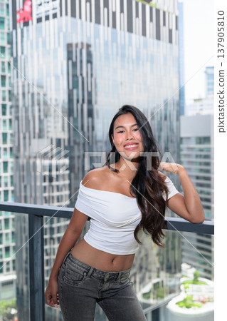 Young Asian woman posing on a high-rise balcony with modern skyscrapers in Kuala Lumpur, Malaysia Young Asian woman posing on a high-rise balcony with modern skyscrapers in Kuala Lumpur, Malaysia 137905810