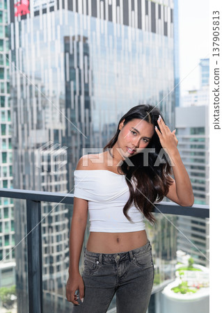 Young Asian woman posing on a high-rise balcony with modern skyscrapers in Kuala Lumpur, Malaysia 137905813