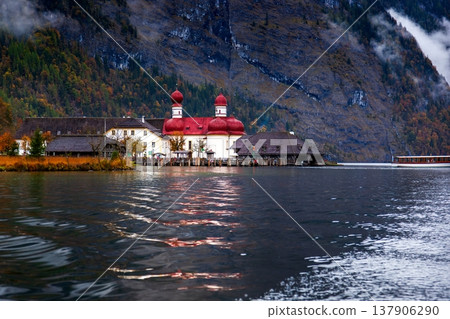 Autumn scenery of St. Bartholomew's Church in Konigssee, Germany, with its lakes and mountains. Autumn scenery of St. Bartholomew's Church in Konigssee, Germany, with its lakes and mountains. 137906290