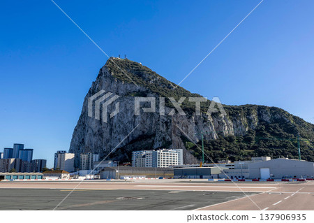 View of the Rock of Gibraltar and surrounding buildings against a clear blue sky during daylight hours View of the Rock of Gibraltar and surrounding buildings against a clear blue sky during daylight hours 137906935