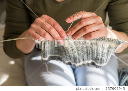 Woman knitting, close-up hands with yarn and knitted scarf. Handicraft hobby concept Woman knitting, close-up hands with yarn and knitted scarf. Handicraft hobby concept 137906943