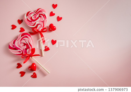 Valentine's Day festive background. Heart-shaped lollipops and heart confetti on pink background with copy space. Love concept 137906973