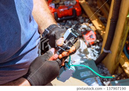 Worker performs wiring tasks while handling tools at construction site Worker performs wiring tasks while handling tools at construction site 137907190