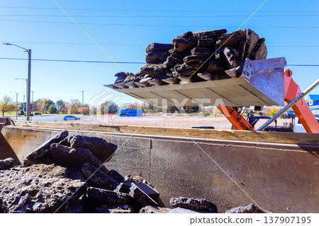 Heavy machinery moves asphalt waste during road construction work Heavy machinery moves asphalt waste during road construction work 137907195