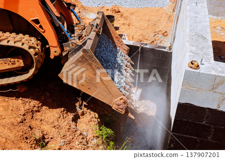 Construction excavator bucket machine pours gravel near building site Construction excavator bucket machine pours gravel near building site 137907201