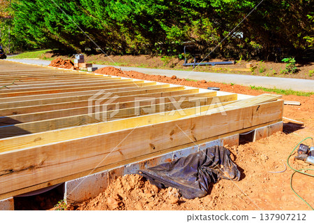 Construction of wooden deck frame takes place in residential area 137907212