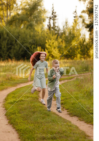 Young Siblings Share Lively Adventure Amid Blooming Flowers And Sundrenched Greenery Young Siblings Share Lively Adventure Amid Blooming Flowers And Sundrenched Greenery 137907742