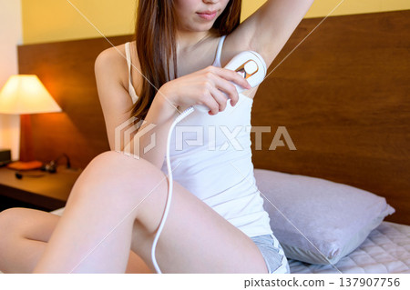 A slender young woman using a home hair removal device, armpit hair removal, skin care, self-hair removal A slender young woman using a home hair removal device, armpit hair removal, skin care, self-hair removal 137907756