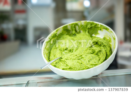 Genoa, liguria, italy. May 18,2024. Pesto genovese in a white bowl with spoon at mercato orientale, genoa vibrant basil sauce ready to serve, fresh and authentic 137907839