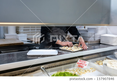 Genoa, liguria, italy. May 18, 2024. Artisan chef preparing freshly made cappelletti pasta for sale in a culinary display at mercato orientale in genoa 137907846