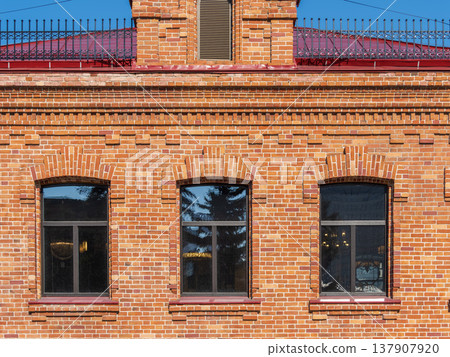 Three windows of the old mansion 19 century with brown bricks wall Three windows of the old mansion 19 century with brown bricks wall 137907920