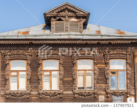 Fragment of the facade of a wooden russian house of the 19th century with carved decor based on folk architecture Fragment of the facade of a wooden russian house of the 19th century with carved decor based on folk architecture 137907921