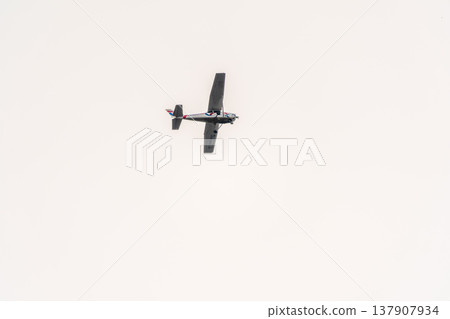 Small ultralight airplane with overhead wing and single propeller flying in sunset sky. 137907934