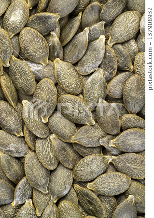 peeled large green pumpkin seeds scattered on the table, a large number of pumpkin seeds dried and ready for subsequent cooking 137908932