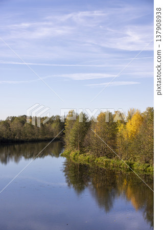 autumn river in sunny weather , beautiful deciduous trees on the riverbank before the fall of leaves, evening time before sunset 137908938