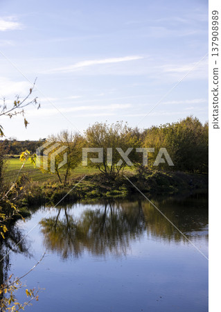 river in sunny weather at sunset, beautiful deciduous trees on the riverbank before the fall of leaves, evening time before sunset river in sunny weather at sunset, beautiful deciduous trees on the riverbank before the fall of leaves, evening time before sunset 137908989