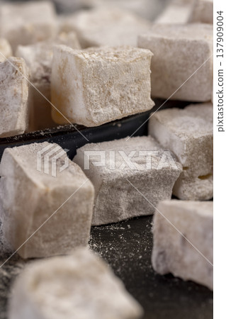 Turkish delight sprinkled with powdered white sugar, cubic sweet white soft pieces of Turkish delight with nuts and dried fruits inside 137909004
