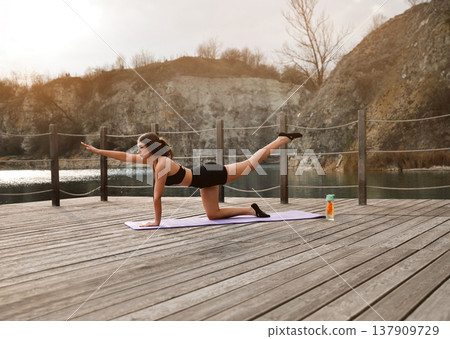 Young Woman Practicing Bird Dog Exercise Outdoors At Lake. Core And Coordination Training Concept Young Woman Practicing Bird Dog Exercise Outdoors At Lake. Core And Coordination Training Concept 137909729