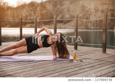 Attractive Woman Practicing Side Plank Yoga Pose Outdoors At Lake. Core Stability And Strength Concept Attractive Woman Practicing Side Plank Yoga Pose Outdoors At Lake. Core Stability And Strength Concept 137909736