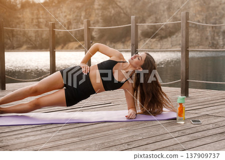 Beautiful Woman Practicing Side Plank Yoga Pose At Lake. Core Strength And Stability Training Concept Beautiful Woman Practicing Side Plank Yoga Pose At Lake. Core Strength And Stability Training Concept 137909737