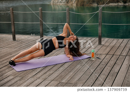 Pretty Woman Practicing Side Plank Yoga Pose Outdoors At Lake. Core Strength And Stability Concept Pretty Woman Practicing Side Plank Yoga Pose Outdoors At Lake. Core Strength And Stability Concept 137909739