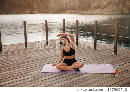 Beautiful Woman Practicing Seated Yoga Stretch Outdoors At Lake. Flexibility And Relaxation Concept Beautiful Woman Practicing Seated Yoga Stretch Outdoors At Lake. Flexibility And Relaxation Concept 137909740