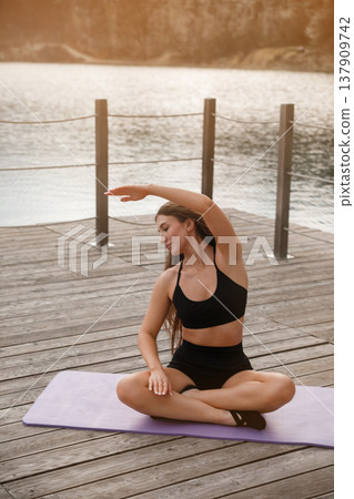 Attractive Woman Practicing Seated Yoga Stretch Outdoors At Lake. Flexibility And Posture Concept 137909742