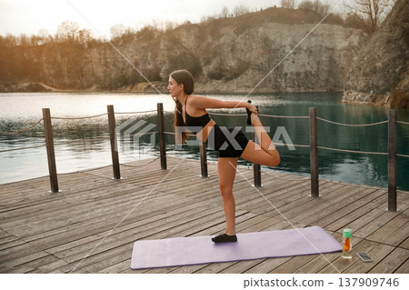Attractive Woman Holding Standing Balance Pose At Lake. Body Control And Stability Training Outdoors Attractive Woman Holding Standing Balance Pose At Lake. Body Control And Stability Training Outdoors 137909746