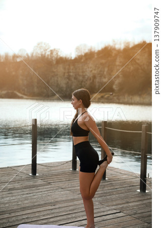 Young Woman Standing Calm After Workout Near Lake. Outdoor Fitness Lifestyle And Recovery Concept Young Woman Standing Calm After Workout Near Lake. Outdoor Fitness Lifestyle And Recovery Concept 137909747
