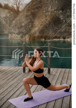 Pretty Woman Performing Forward Lunge Exercise On Yoga Mat At Lake. Lower Body Strength And Balance Concept Pretty Woman Performing Forward Lunge Exercise On Yoga Mat At Lake. Lower Body Strength And Balance Concept 137909748