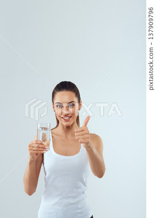 Portrait of beautiful woman on isolated studio background, hold water glass. Drink water. Diet concept Portrait of beautiful woman on isolated studio background, hold water glass. Drink water. Diet concept 137909796