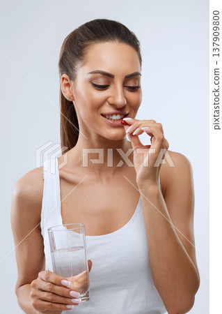 Happy Smiling Woman Taking Pill With Cod Liver Oil Omega-3 And Holding A Glass Of Fresh Water Happy Smiling Woman Taking Pill With Cod Liver Oil Omega-3 And Holding A Glass Of Fresh Water 137909800