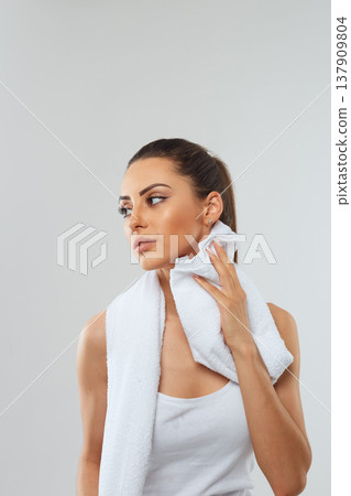 Sports woman after workout with towel on his shoulders on a grey background Sports woman after workout with towel on his shoulders on a grey background 137909804