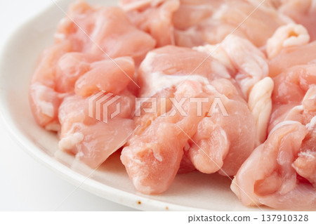 A close-up of raw chicken thigh meat cut into chunks and placed on a plate. A close-up of raw chicken thigh meat cut into chunks and placed on a plate. 137910328