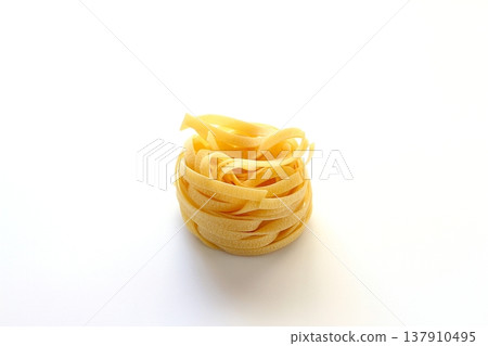 White background with dried tagliatelle pasta. White background with dried tagliatelle pasta. 137910495