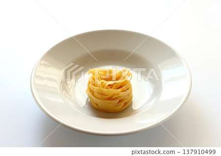 White background with dried tagliatelle pasta. White background with dried tagliatelle pasta. 137910499