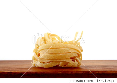 White background with dried tagliatelle pasta. White background with dried tagliatelle pasta. 137910644