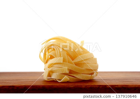 White background with dried tagliatelle pasta. White background with dried tagliatelle pasta. 137910646