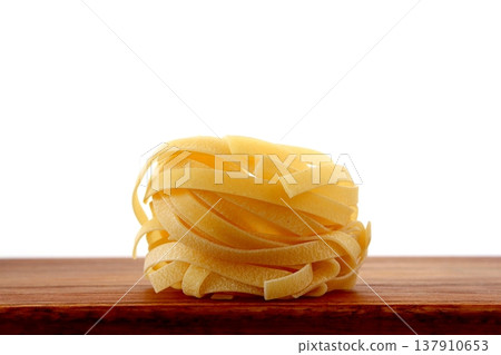 White background with dried tagliatelle pasta. White background with dried tagliatelle pasta. 137910653