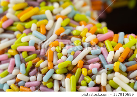 特寫:巧克力甜甜圈上撒滿了五彩繽紛的糖屑。 特寫:巧克力甜甜圈上撒滿了五彩繽紛的糖屑。 137910699