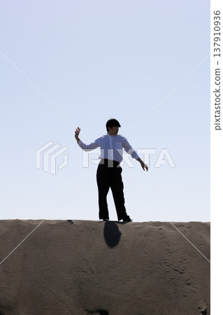 Silhouette of a man standing on the sand 137910936
