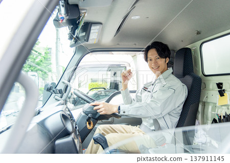 A man in work clothes riding in a truck 137911145