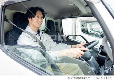 一名身穿工作服的男子坐在卡車裡 137911146