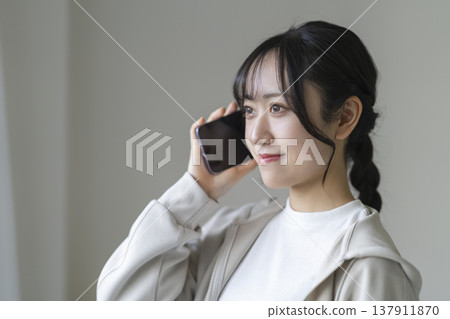 A smiling young woman talking on a smartphone A smiling young woman talking on a smartphone 137911870